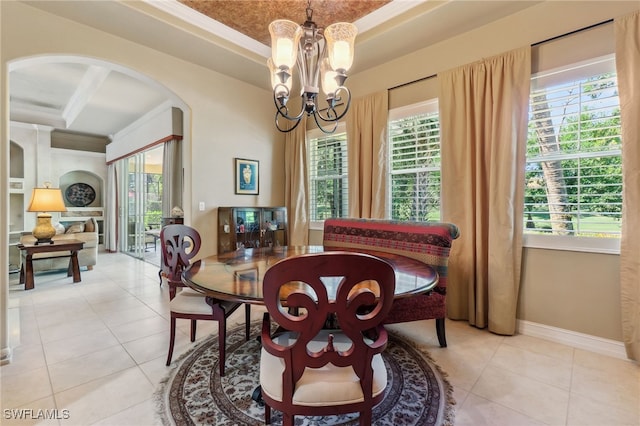 dining space with a tray ceiling, arched walkways, plenty of natural light, and a chandelier