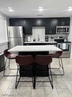 kitchen with a sink, appliances with stainless steel finishes, a breakfast bar area, and light countertops