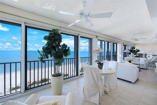 sunroom / solarium with a ceiling fan and a water view