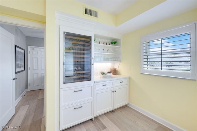 bar with visible vents, light wood-style flooring, and baseboards