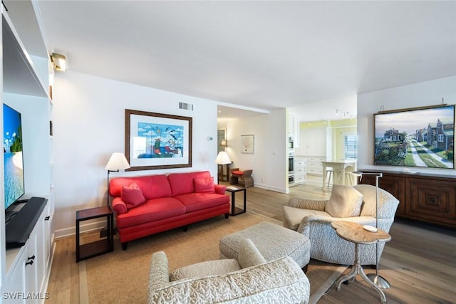 living room featuring visible vents, baseboards, and light wood finished floors