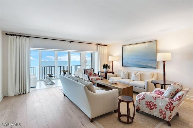 living area with light wood-type flooring and a water view