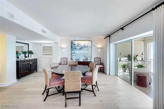 dining space with baseboards, visible vents, and light wood finished floors