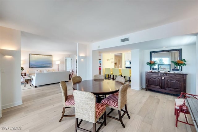 dining space featuring light wood-style floors, visible vents, and baseboards