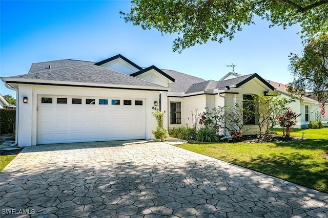 ranch-style house featuring a front yard, roof with shingles, stucco siding, a garage, and decorative driveway