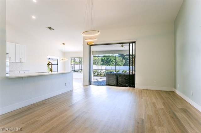 unfurnished living room featuring a sink, visible vents, baseboards, and light wood-style flooring