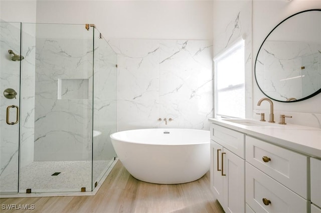 bathroom with a marble finish shower, a freestanding bath, vanity, and wood finished floors