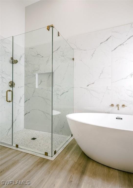 bathroom with a freestanding tub, a marble finish shower, and wood finished floors