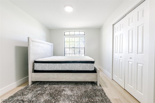 bedroom featuring light wood-style flooring, baseboards, and a closet
