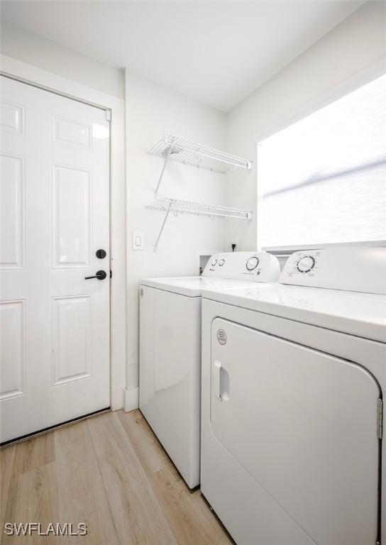 laundry room with separate washer and dryer, laundry area, and light wood finished floors