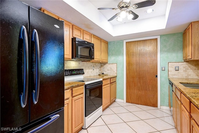 kitchen with a tray ceiling, light tile patterned flooring, ceiling fan, decorative backsplash, and black appliances