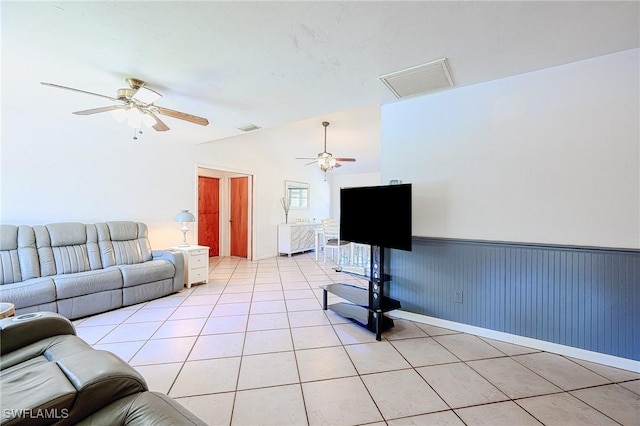 living area featuring light tile patterned floors, visible vents, lofted ceiling, and wainscoting