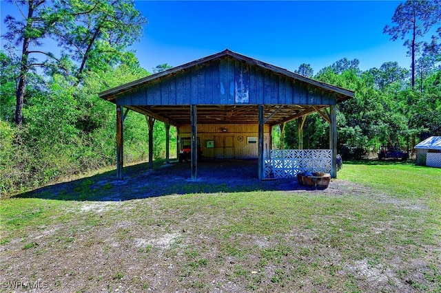 view of pole building featuring a carport, a yard, and driveway