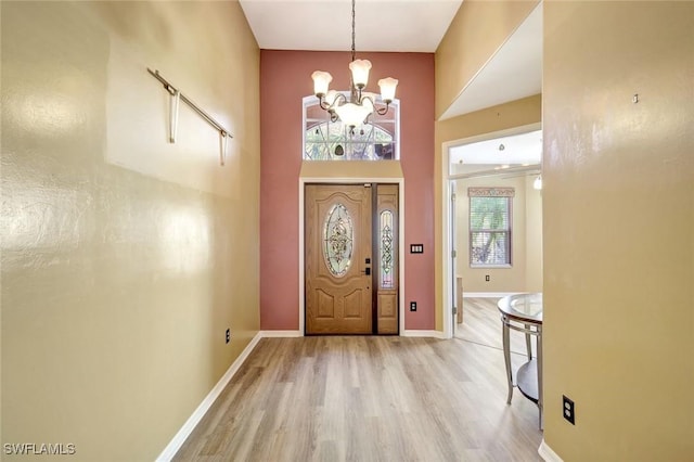 foyer featuring baseboards, an inviting chandelier, and wood finished floors