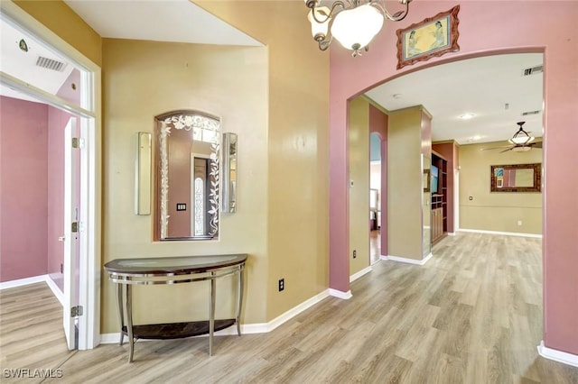 hallway with visible vents, arched walkways, baseboards, and wood finished floors