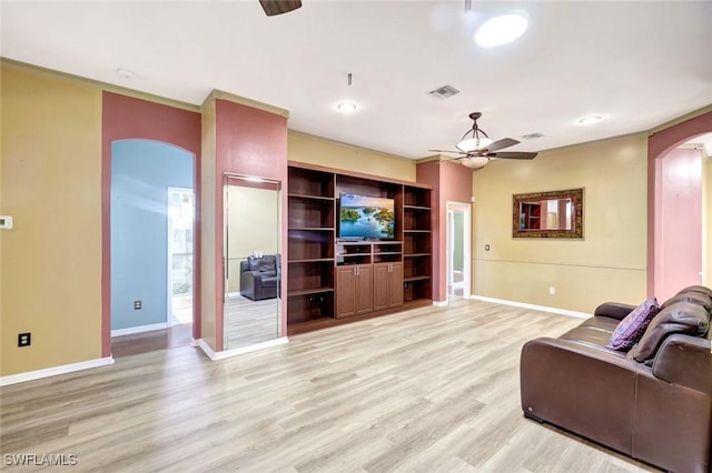 living area with a ceiling fan, visible vents, baseboards, arched walkways, and light wood-type flooring