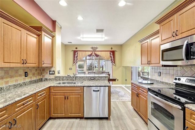 kitchen with visible vents, light wood-type flooring, a peninsula, stainless steel appliances, and a sink