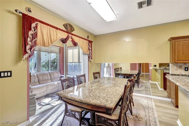 dining area with crown molding, baseboards, visible vents, and light wood-type flooring