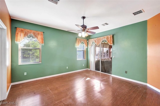 empty room with baseboards, wood finished floors, visible vents, and ceiling fan