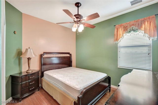 bedroom featuring a ceiling fan, wood finished floors, visible vents, and baseboards