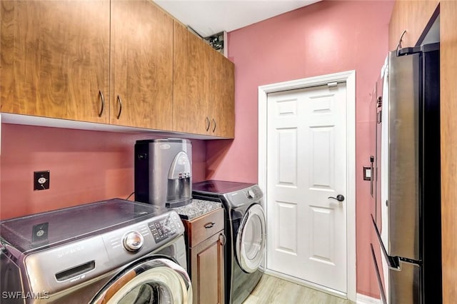 laundry area with cabinet space, light wood-style floors, and washing machine and clothes dryer