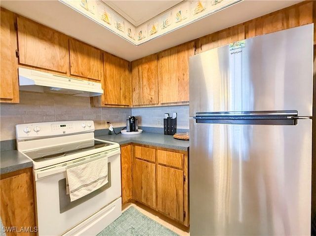 kitchen featuring under cabinet range hood, electric range, brown cabinets, and freestanding refrigerator