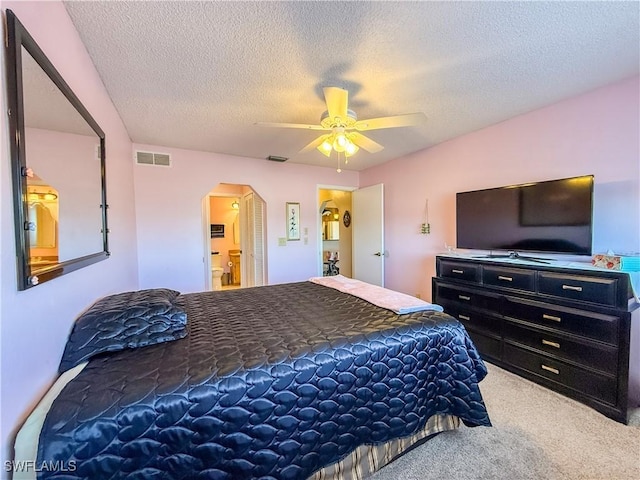 carpeted bedroom featuring visible vents, arched walkways, a textured ceiling, and a ceiling fan