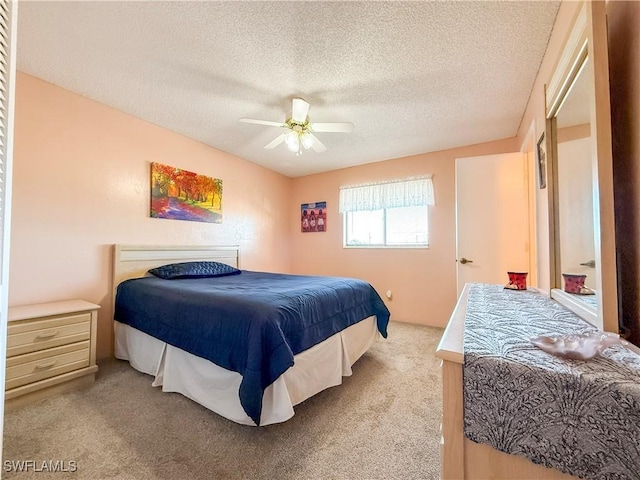 bedroom with ceiling fan, carpet, and a textured ceiling