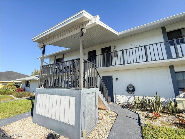 exterior space with stairway, a porch, and stucco siding