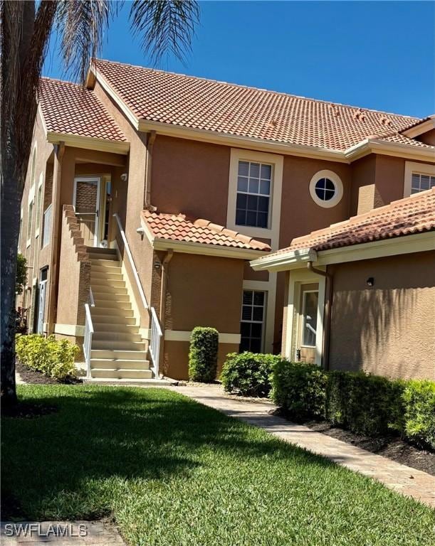 mediterranean / spanish home featuring stucco siding, a tile roof, and a front yard