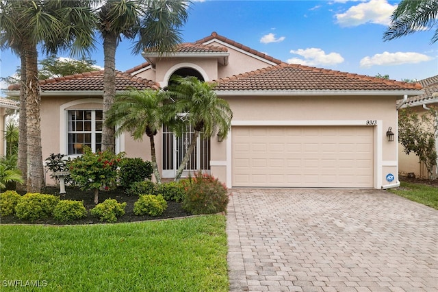 mediterranean / spanish-style house with a tile roof, decorative driveway, an attached garage, and stucco siding