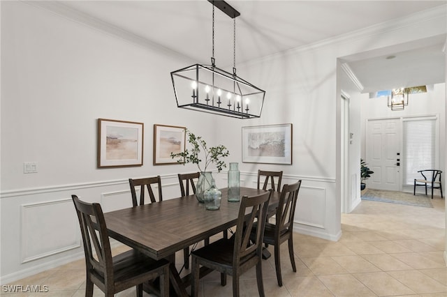 dining area featuring crown molding, a wainscoted wall, light tile patterned floors, an inviting chandelier, and a decorative wall