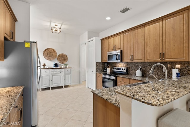 kitchen with tasteful backsplash, stone counters, appliances with stainless steel finishes, and a sink