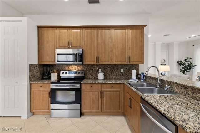 kitchen featuring a sink, stainless steel appliances, brown cabinets, and tasteful backsplash