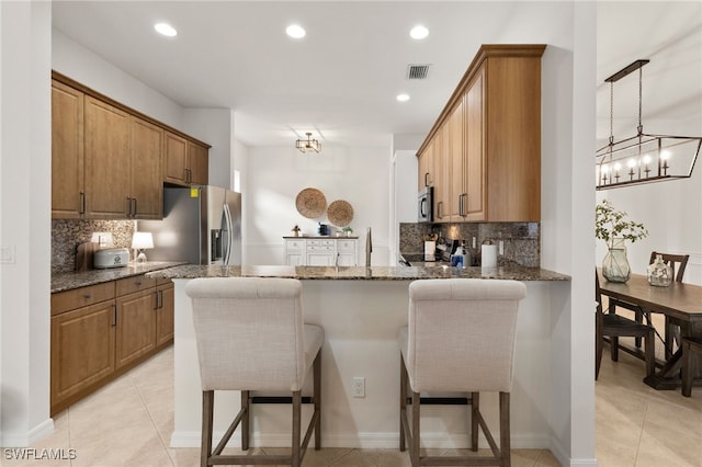 kitchen featuring a breakfast bar area, stainless steel appliances, visible vents, and a peninsula