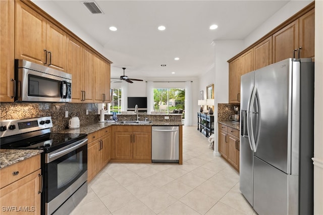 kitchen with visible vents, a peninsula, a sink, decorative backsplash, and appliances with stainless steel finishes