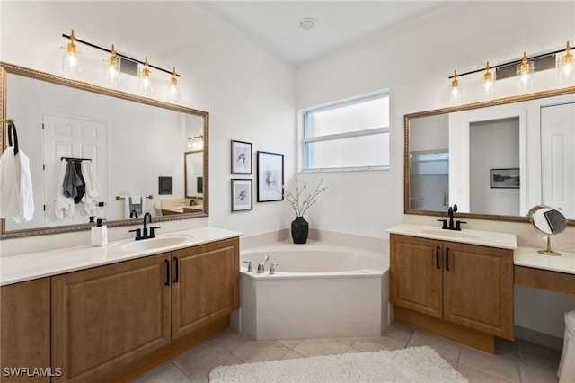 bathroom featuring tile patterned flooring, two vanities, a bath, and a sink