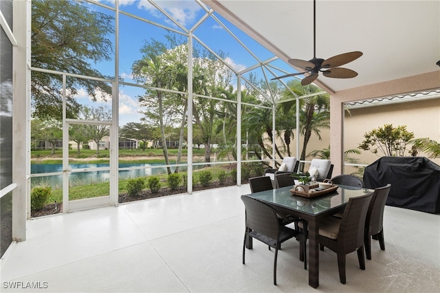 sunroom with a ceiling fan and a water view