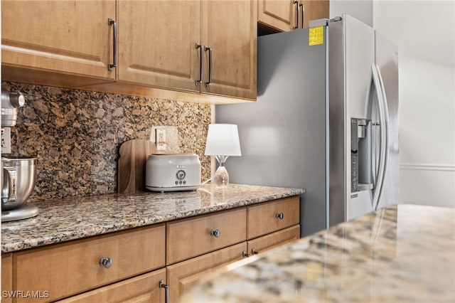 kitchen featuring light stone countertops, tasteful backsplash, and stainless steel refrigerator with ice dispenser