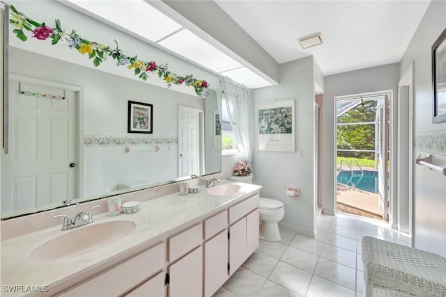 bathroom featuring a sink, toilet, double vanity, and tile patterned flooring