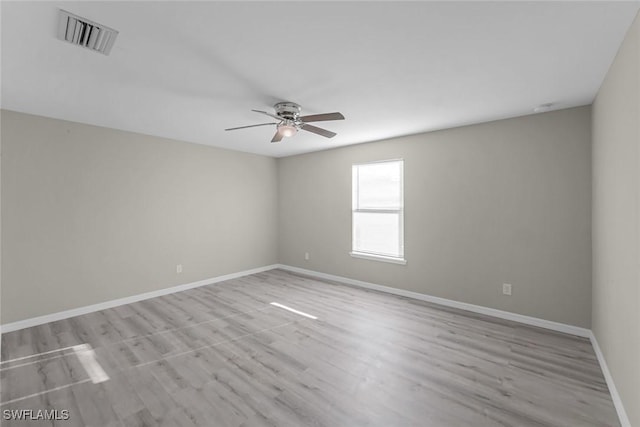 spare room featuring visible vents, baseboards, wood finished floors, and a ceiling fan