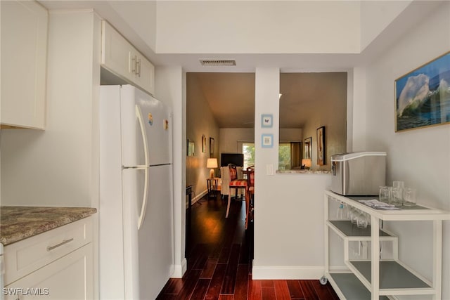 kitchen featuring dark wood finished floors, white cabinets, visible vents, and freestanding refrigerator