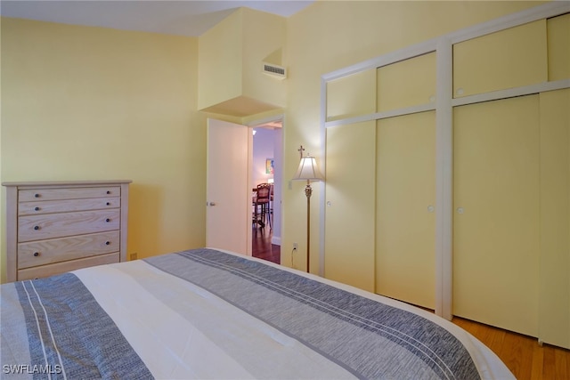 bedroom featuring visible vents, multiple closets, and wood finished floors