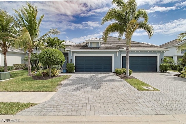 view of front of home featuring stucco siding, a front lawn, decorative driveway, cooling unit, and an attached garage