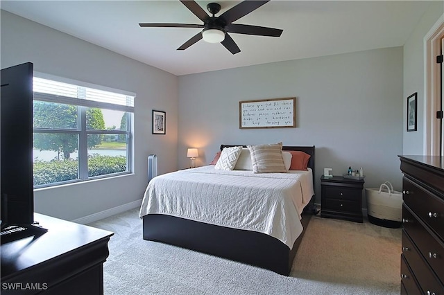 bedroom featuring light colored carpet, baseboards, and ceiling fan