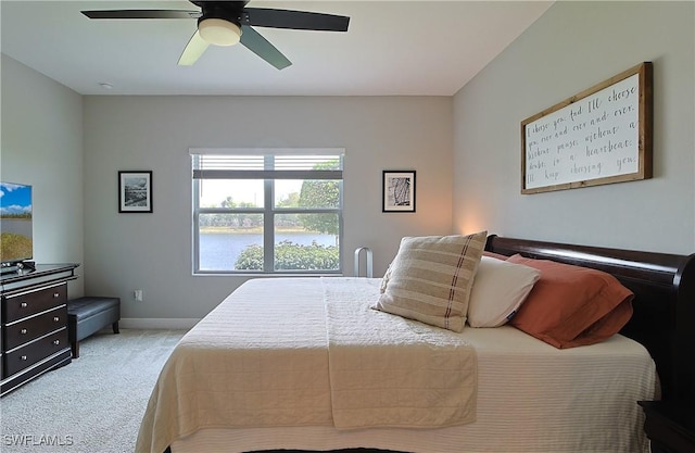 carpeted bedroom featuring baseboards, a water view, and ceiling fan