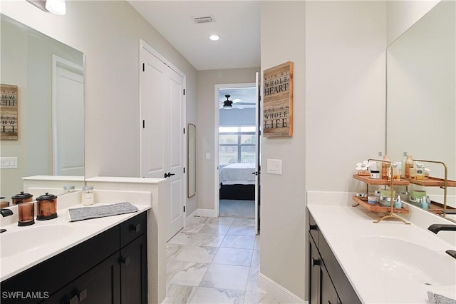 ensuite bathroom featuring recessed lighting, marble finish floor, two vanities, and a sink