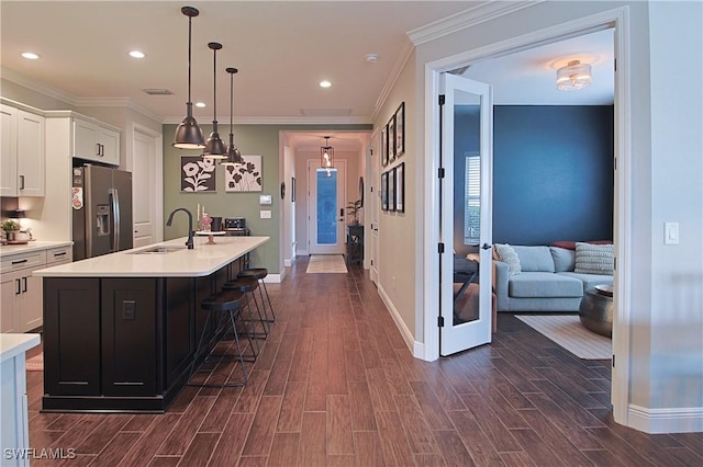 kitchen featuring wood finish floors, a sink, white cabinetry, stainless steel fridge, and light countertops