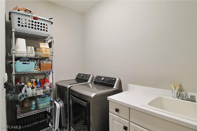 clothes washing area featuring a sink, cabinet space, and separate washer and dryer