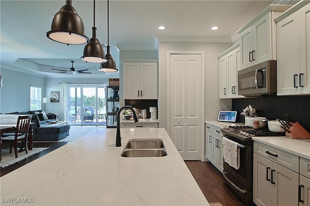 kitchen featuring stainless steel microwave, black gas stove, ornamental molding, and a sink